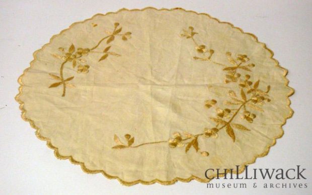 Round cream-coloured cotton table cover with scalloped edge and embroidered floral pattern