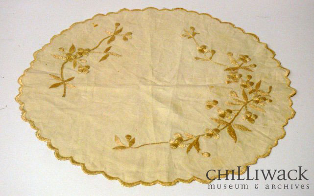 Round cream-coloured cotton table cover with scalloped edge and embroidered floral pattern