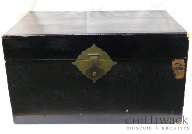 Black painted wooden trunk with four rectangular metal hinges and front clasp
