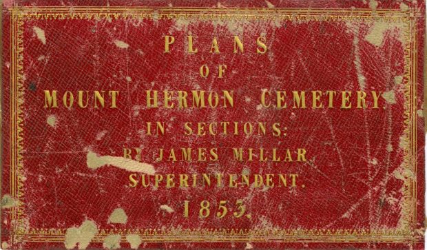 Color photo of a red and gold cover page of the plans of Mount Hermon Cemetery by James Miller. The cover is old and tattered, and the words are written in golden letters.