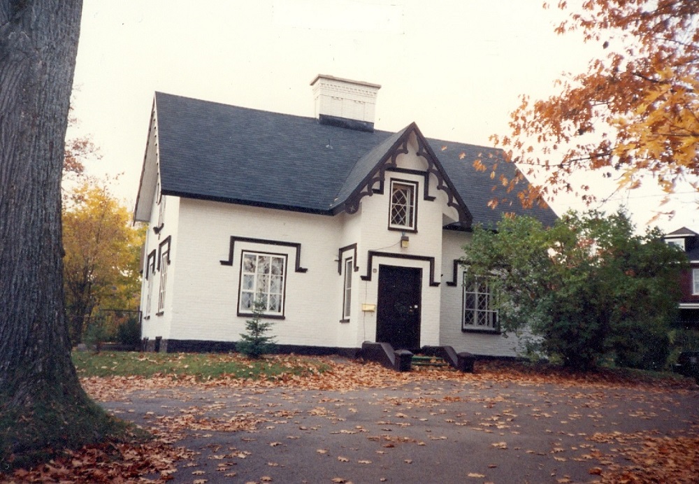 Coloured picture of a white house surrounded by fall foliage