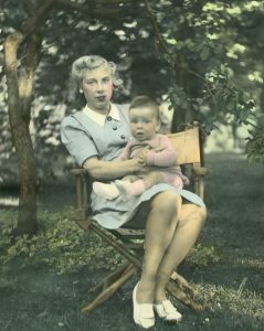 coloured picture of a woman holding a baby boy in her lap. they are outside my a large tree.