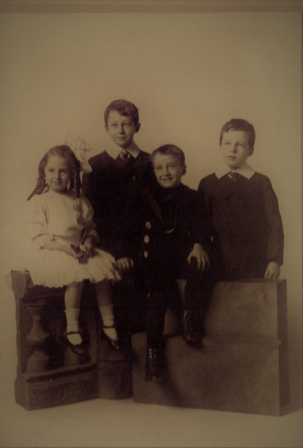 Sepia colour photo of three kids in a family photo