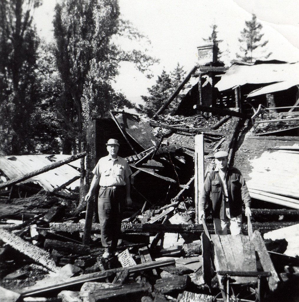 Black and white picture of a man standing in the middle of rubble after a fire