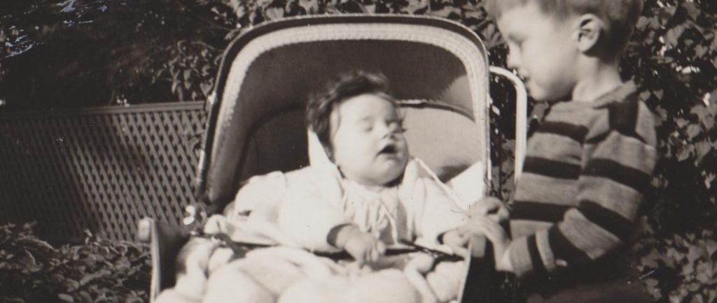 Black and white picture of a little boy and a little baby in a carriage