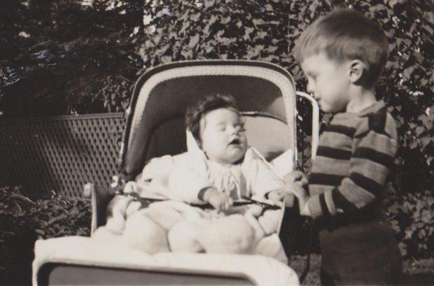 Black and white picture of a little boy and a little baby in a carriage