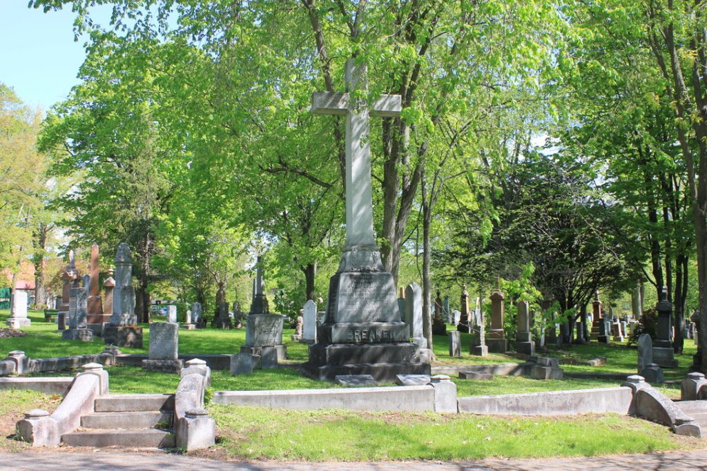 Coloured picture of a cemetery gravestone surrounded by tree and other stones