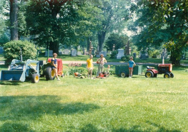 Young man posing with tractor and lawnmowers