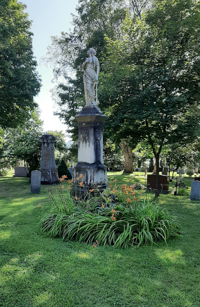 Marble statue monument surrendered by trees in the shade