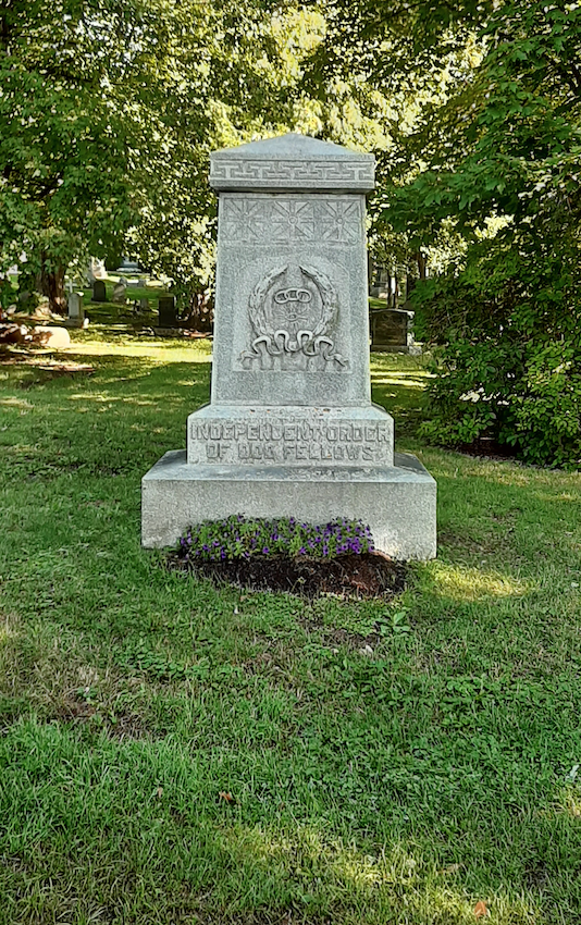 Coloured picture of a tombstone in the grass and surrounded by trees