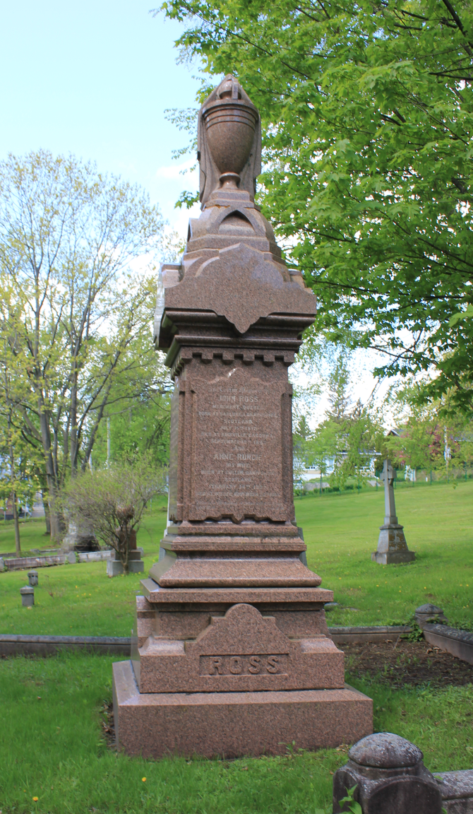 Coloured picture of a red tombstone in the grass and surrounded by trees