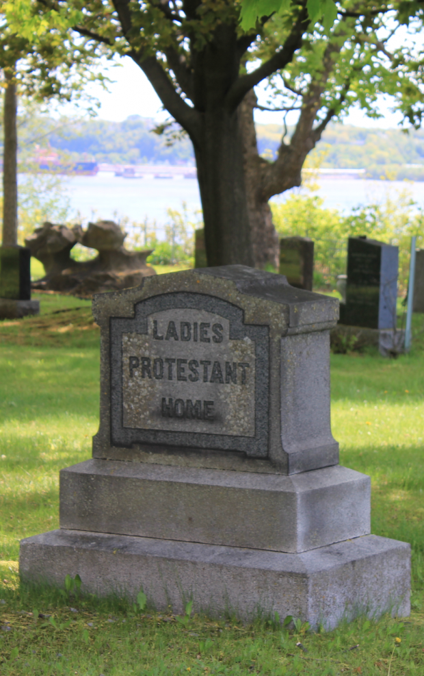 Coloured picture of a tombstone in the grass and surrounded by trees