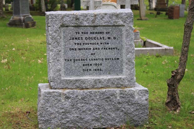 Grey headstone with text on the front in the grass