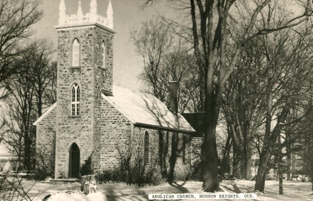 Old black and white photograph, long shot taken in winter, façade and side-view of a stone church and its square steeple.
