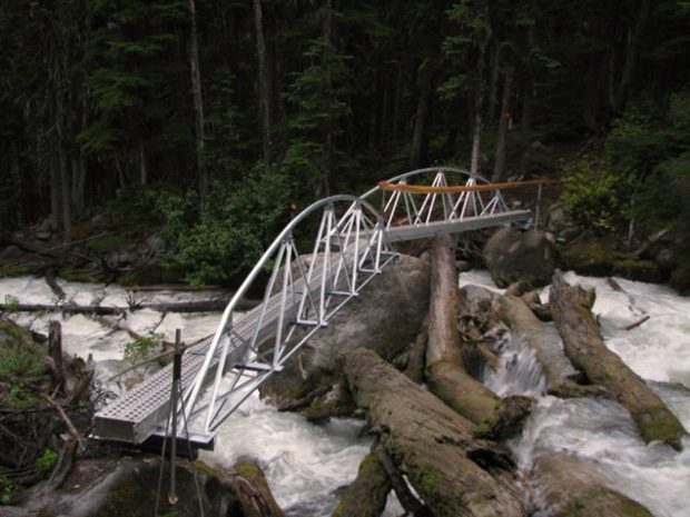 Steel footbridge with brand new metal hand railings over a creek on the trail to the Harrison Hut.