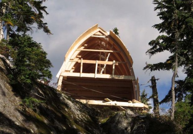 The wood frame is still exposed because the wall at the end hasn’t been added. The under layer of the roof has been added and the arched beams are clearly visible on the second floor.