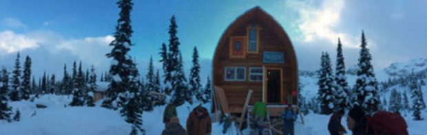 The Hut is under clear blue skies and several work-crew members are busy working out front in the snow.