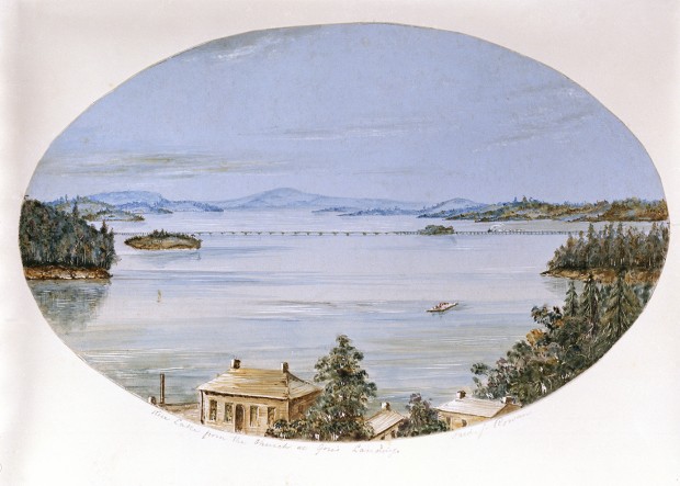 photograph of a watercolour painting showing roofs of houses in the foreground, hills in the distance and cam water in between. In the middle distance a long bridge is being crossed by a steam engine with an indeterminate number of cars. Nearer by is a barge