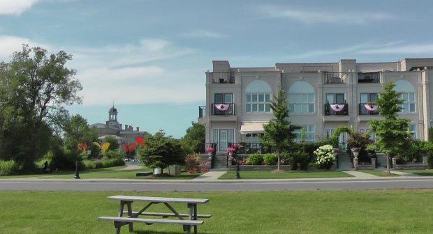 picnic bench sits on a green lawn in front of a two-story condominium. in the distance is a large building with cupola