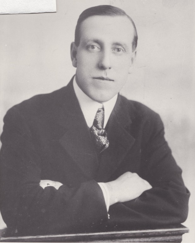 W.H. Bunting has his arms folded in this photograph. He looks serious and he is wearing a dark suit, light shirt and tie.