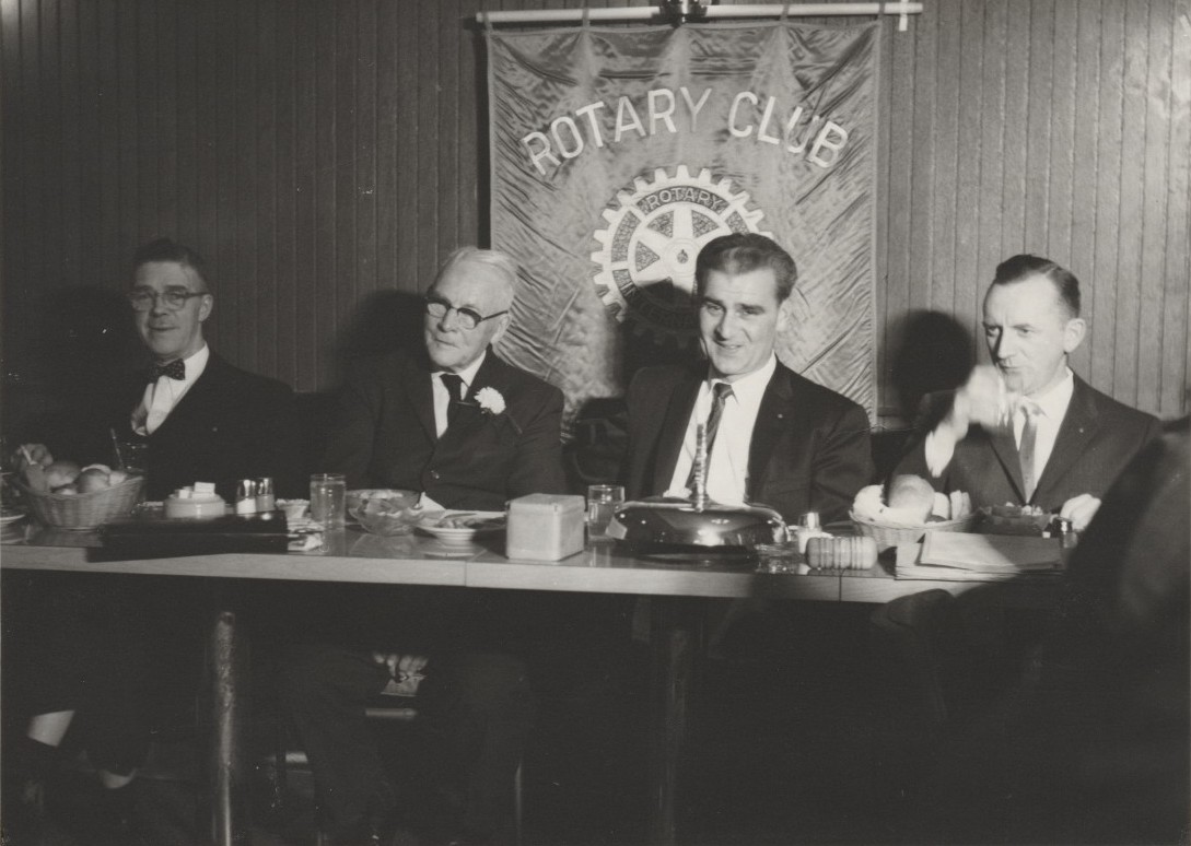 four men formally dressed sitting at a table facing the camera
