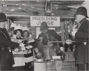 fur queen contestants and keystone kops inside log cabin laughing