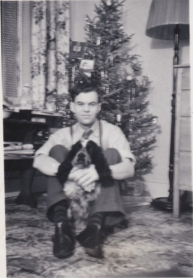 Erik Wadelius is sitting on floor in front of a Christmas tree.