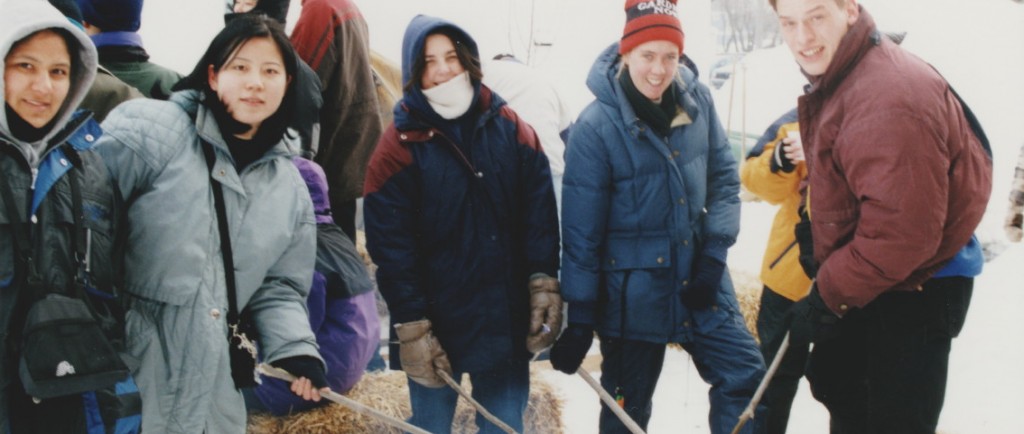 A number of young people dressed in winter gear roasting bannock over a fire. The activity was part of the 1999 Trappers' Festival.