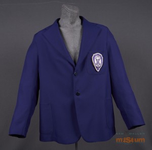 The jacket is single breasted and purple throughout. There is a partial inner lining of a slightly lighter purple. The jacket has two side pockets and one breast pocket on the left side. The Elks crest is sewn to this pocket. The crest reads 