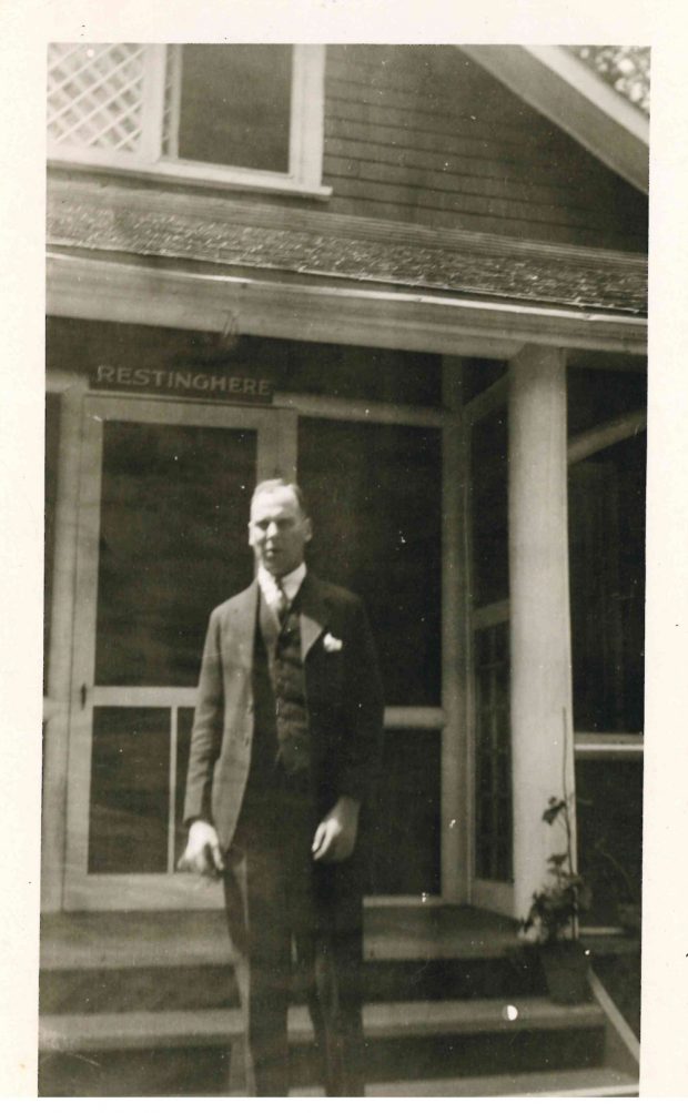 Photo of person in front of Lougheed Banff cabin (sign above door with cabin name RestingHere)
