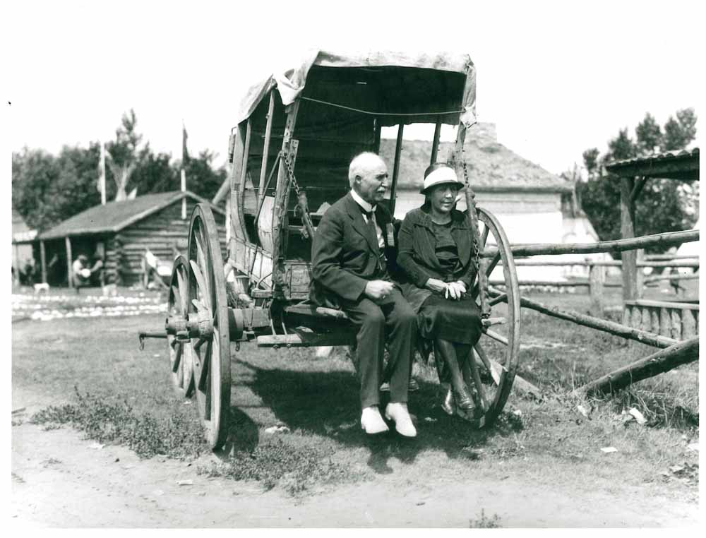 Belle and J.J. McHugh seated on the back of an old covered wagon at the Stampede in 1925