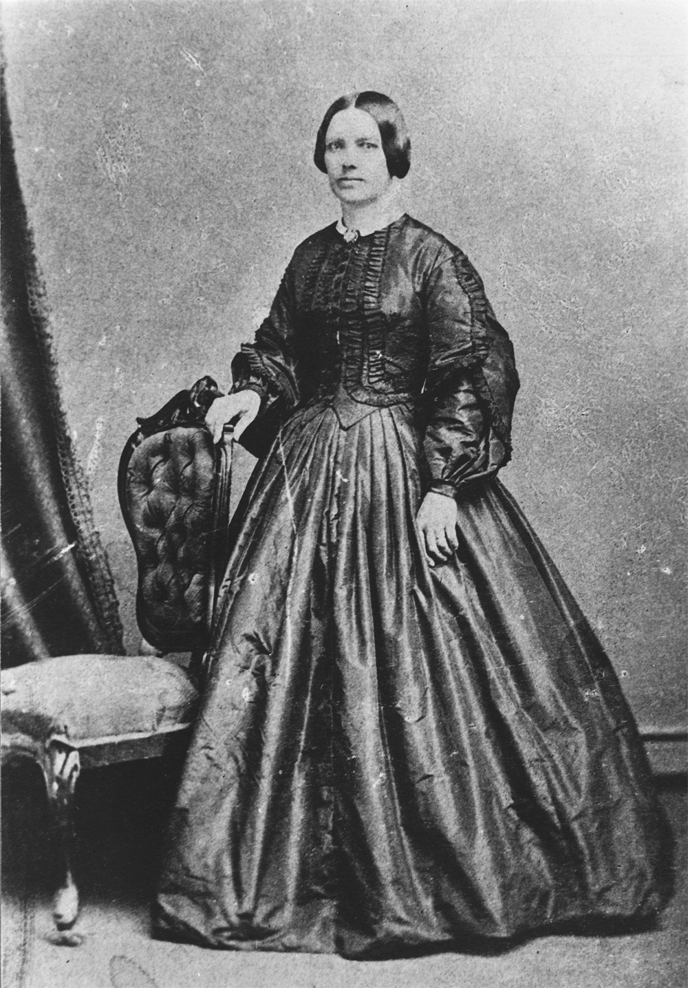 Photo of Lady Strathcona (Isabella Sophia Hardisty) standing beside a chair wearing a formal dress