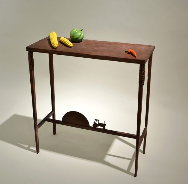 Table with a silhouette tractor on the leg structure, and vegetables on the surface
