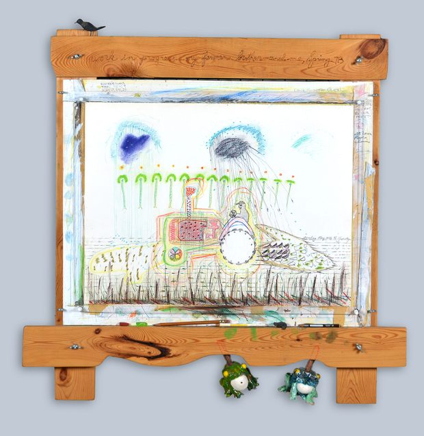 Drawing of farmer on tractor, wood frame has a bird, pencils, and ceramic frogs.