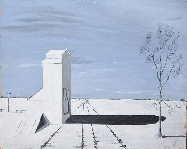 A grain elevator casting a shadow on snowy ground