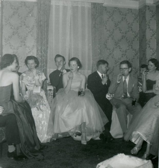 Elegant young people at a party in a black and white photo; seated.