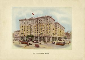 Façade extérieure de l’hôtel avec tramways et calèches et de nombreux promeneurs.