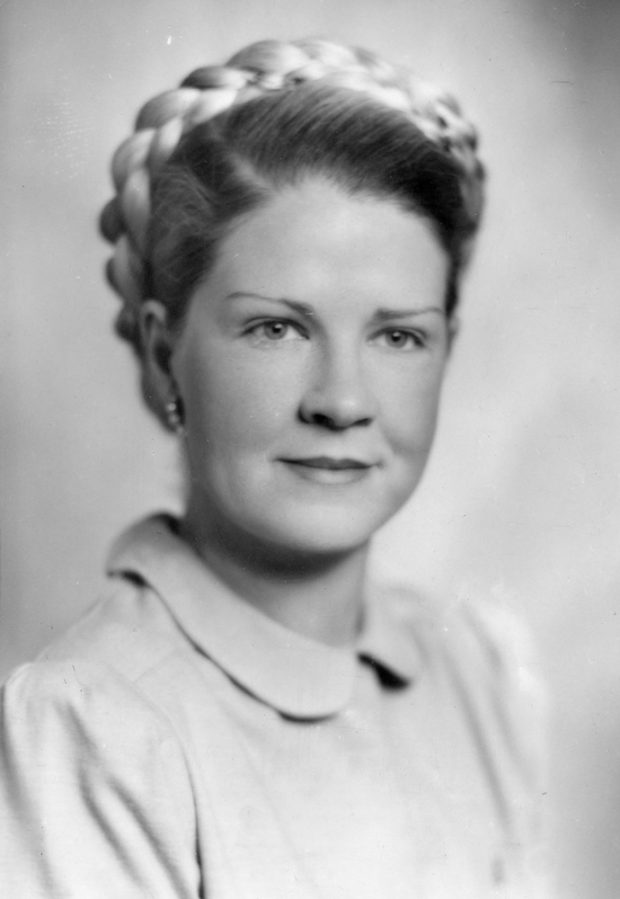 Black and white portrait of a delicately smiling woman with a braided undo.