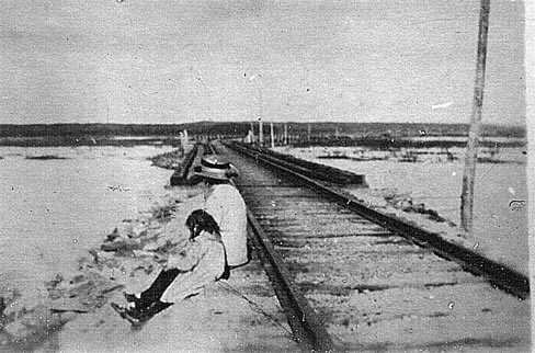 Two people sitting on the railway across the salt marsh
