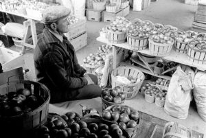 A man sitting at his fruit and vegetable stall at the public market