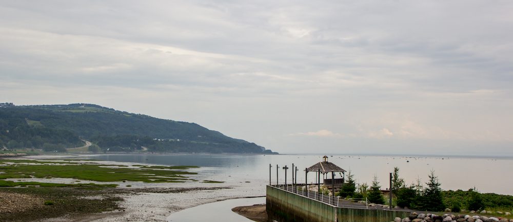 View of the bay in Saint-Joseph-de-la-Rive taken from the site of the Musée maritime de Charlevoix. A wooden dock in the foreground juts into the river.