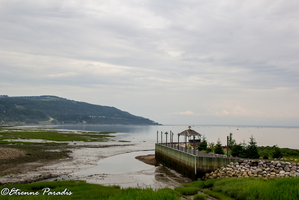 View of the bay in Saint-Joseph-de-la-Rive taken from the site of the Musée maritime de Charlevoix. A wooden dock in the foreground juts into the river.