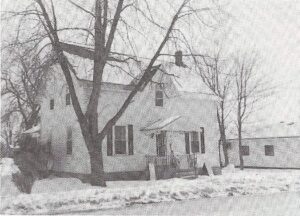 Black and white photograph of a small, two-storey white house in winter at 235 Ottawa Street in Almonte.