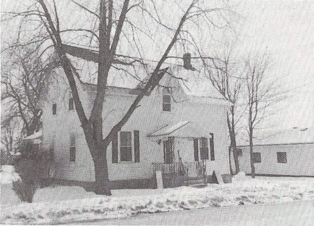 Black and white photograph of a small, two-storey white house in winter at 235 Ottawa Street in Almonte.