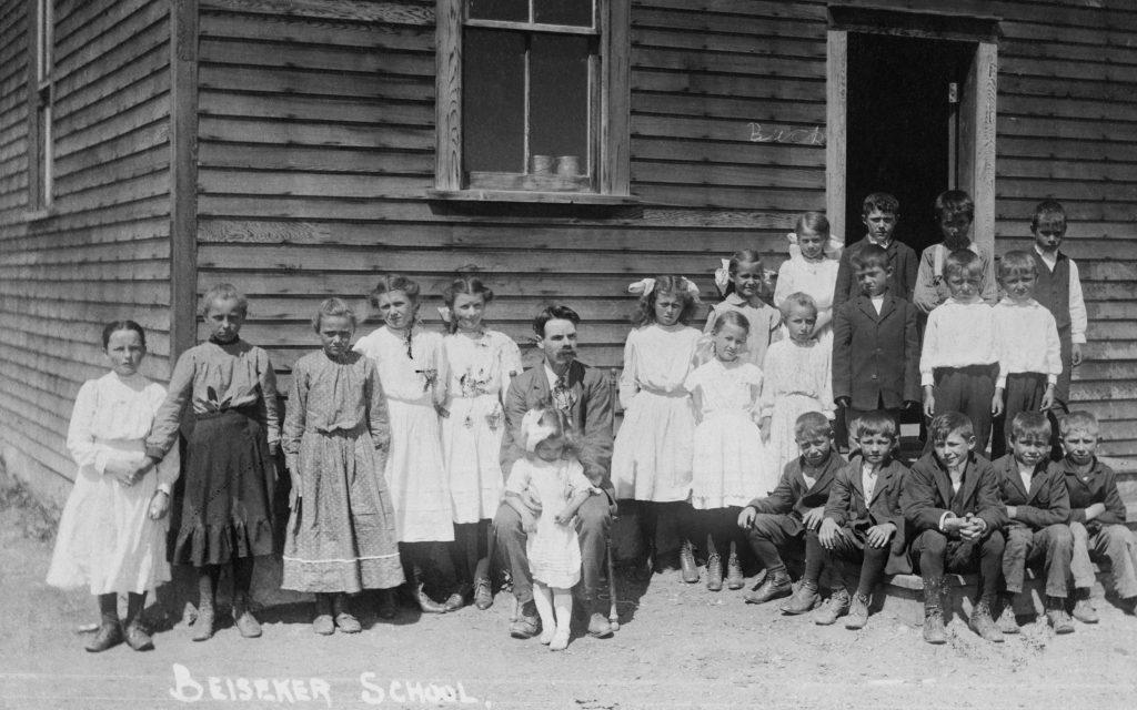 Class photo of children standing outside clapboard school in Beiseker.