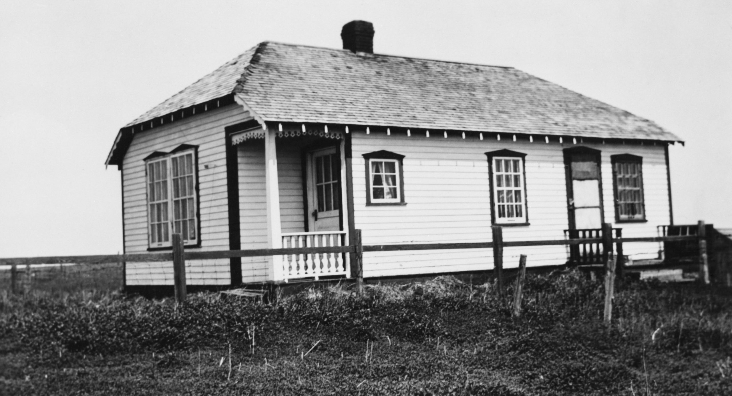 Teacherage cottage on open prairie with wood rail fence