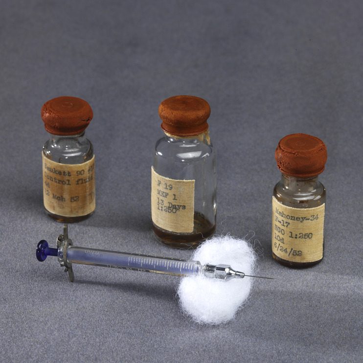 Three vaccine bottles with syringe on cottonball, circa 1952.