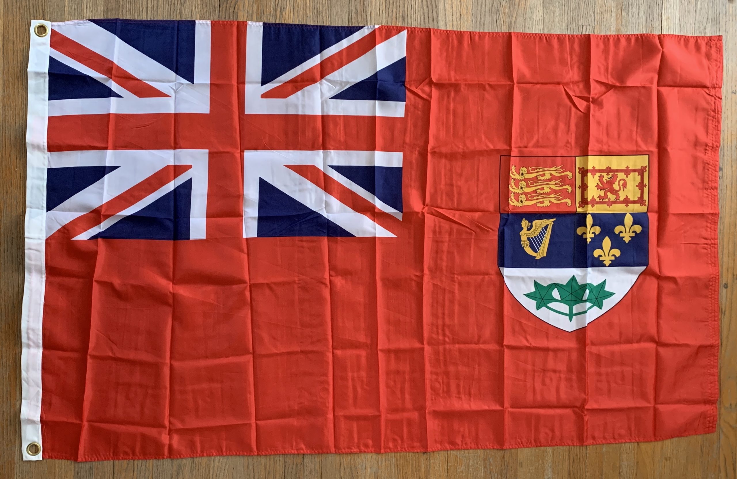 English Ensign flag, red backdrop with Union Jack in top left corner and Canadian Coat of Arms shield on middle right