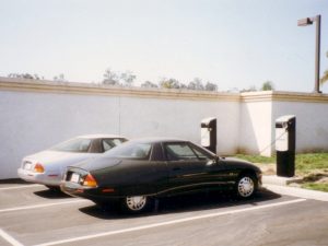 Colour photograph of two electric cars parked side-by-side at a charging station.