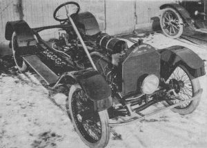 Black and white photograph of a skeletonized automobile parked in a snowy parking lot. Writing on its radiator reads “GALT MOTOR CO / GALT, ONTARIO”